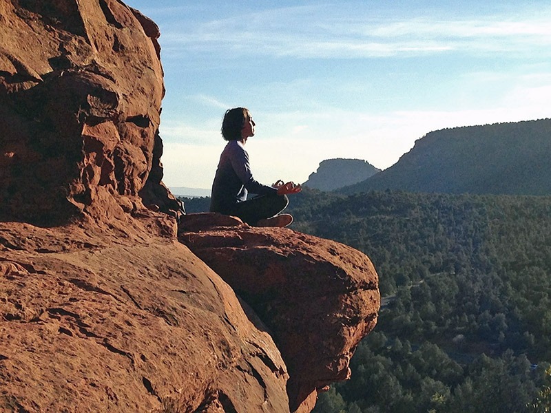 Woman meditating on cliff edge
